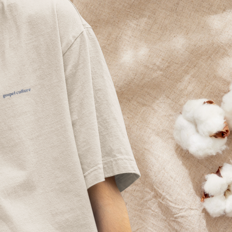 Beige t-shirt with 'gospel culture' text on a textured beige background with cotton flowers.