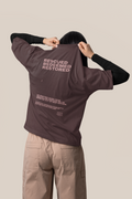 Person wearing a jacket with 'RESCUED REDEEMED RESTORED' text on the back against a beige background