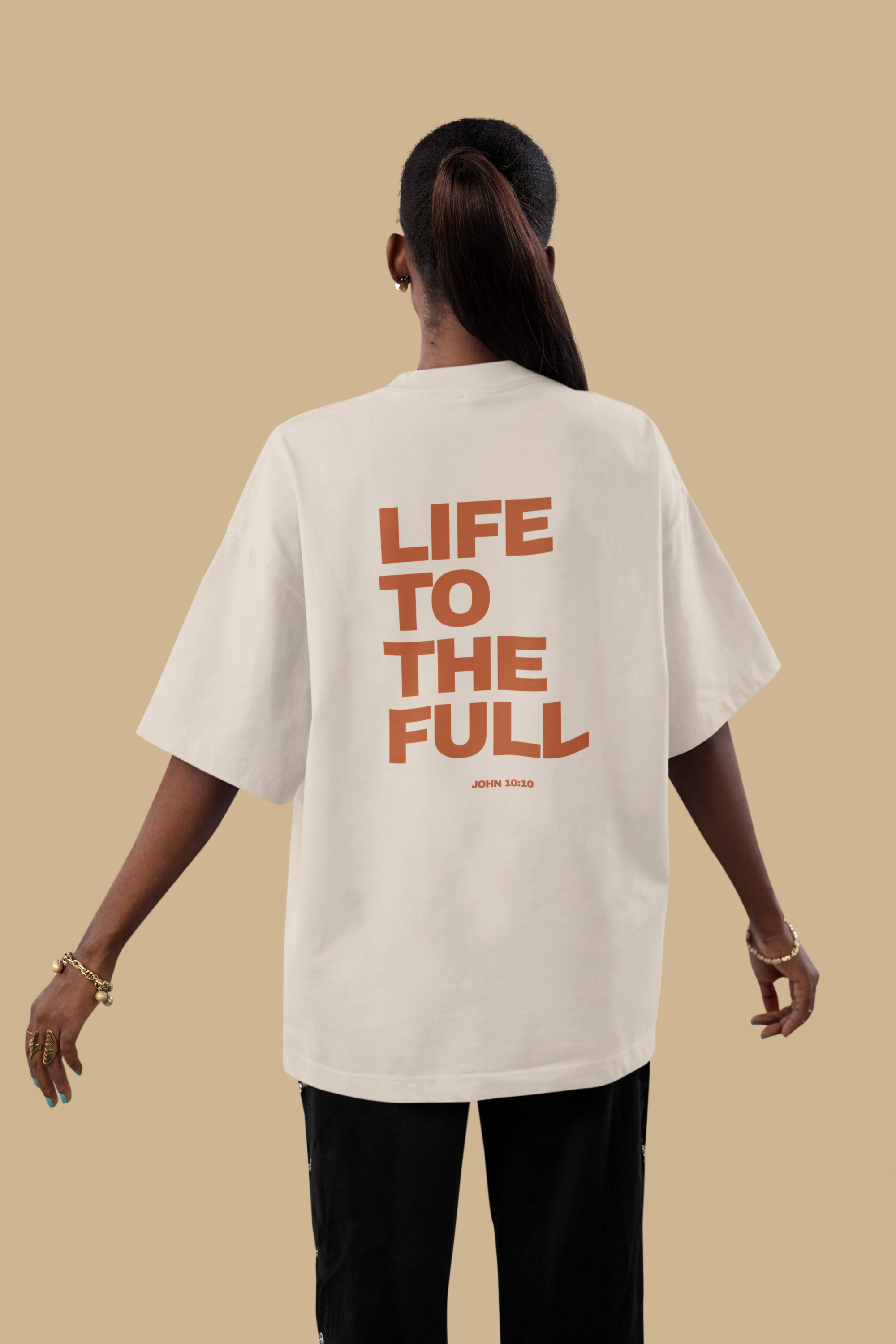 Person wearing a white t-shirt with 'LIFE TO THE FULL' text on the back against a beige background