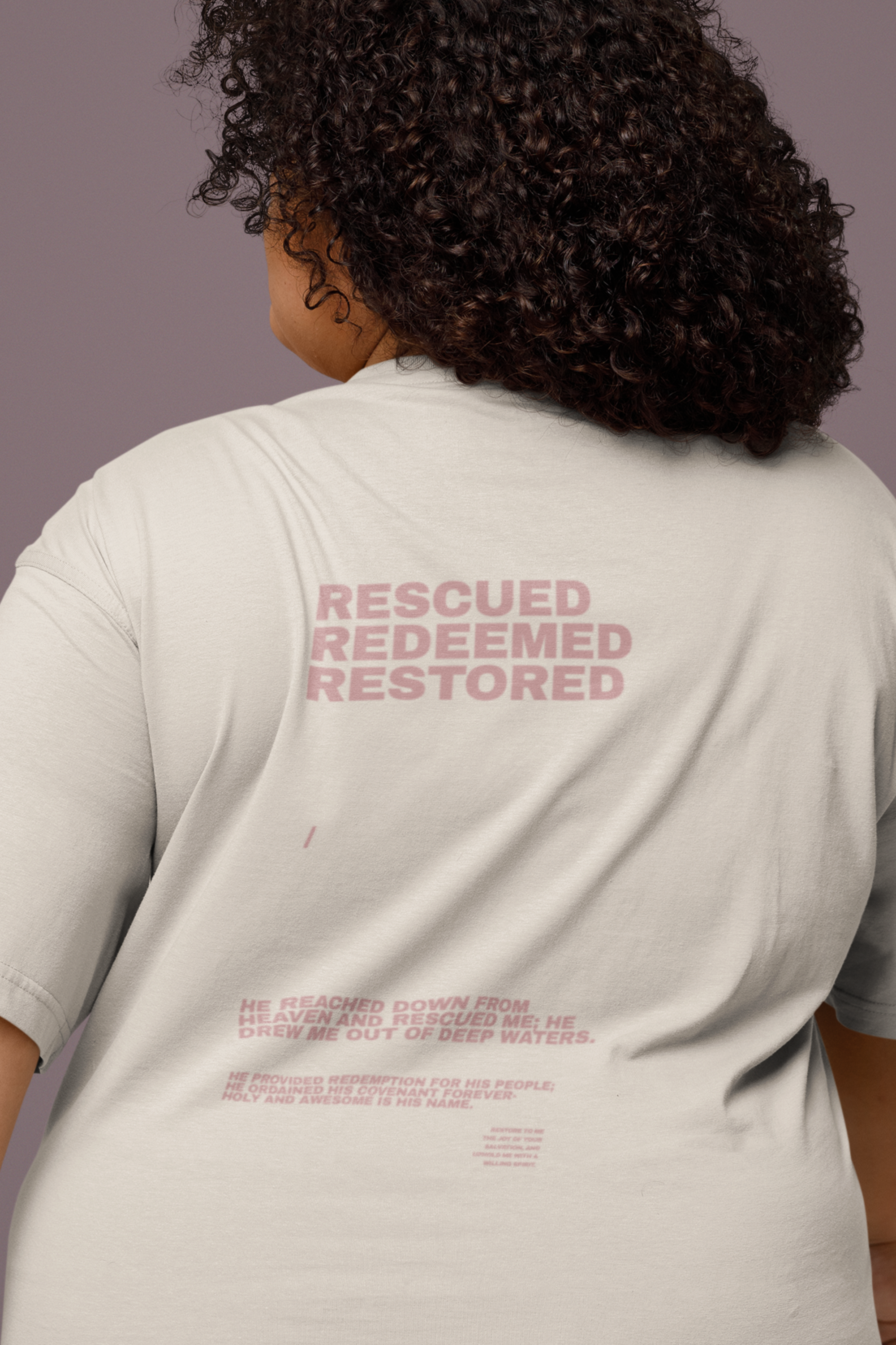 Person wearing a light beige t-shirt with 'Rescued Redeemed Restored' text on the back.