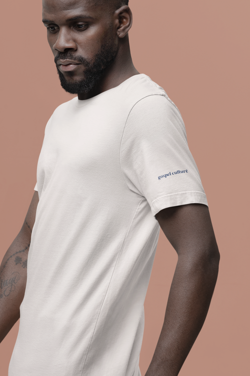 Man wearing a white t-shirt with a gospel culture brand logo on a brown background