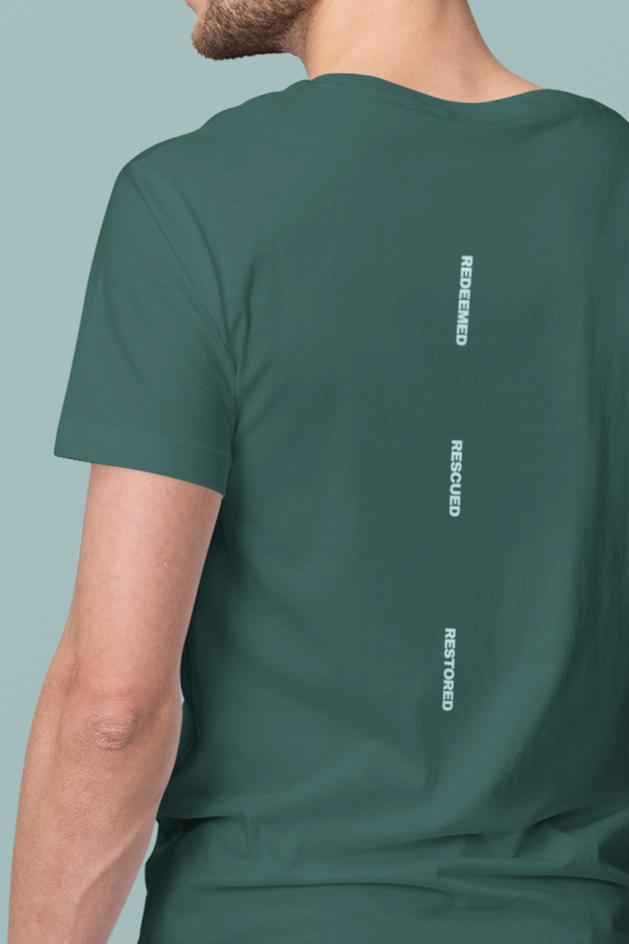 Green t-shirt with Christian text on the back against a gray background