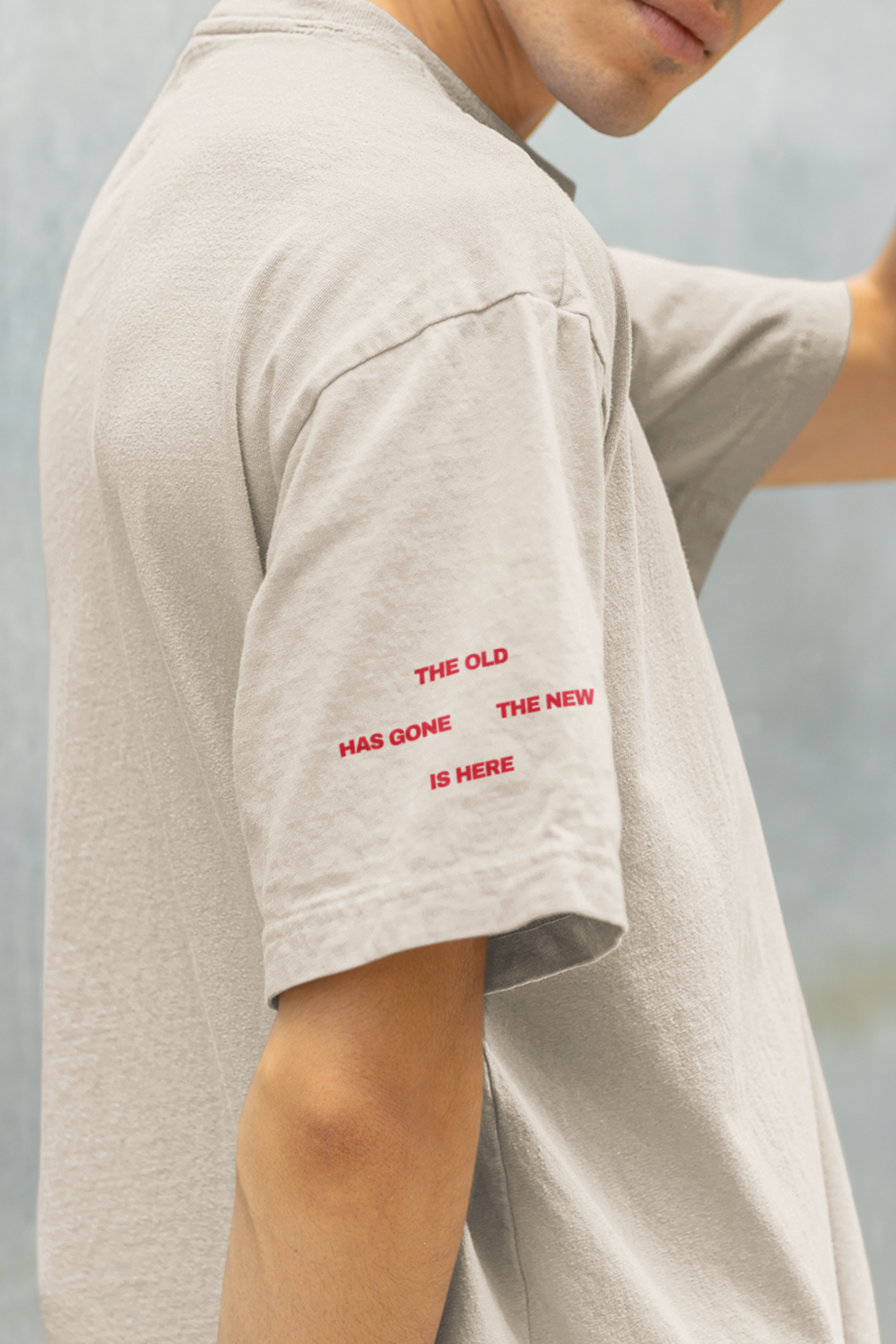Person wearing a beige t-shirt with red bible text on a blurred background