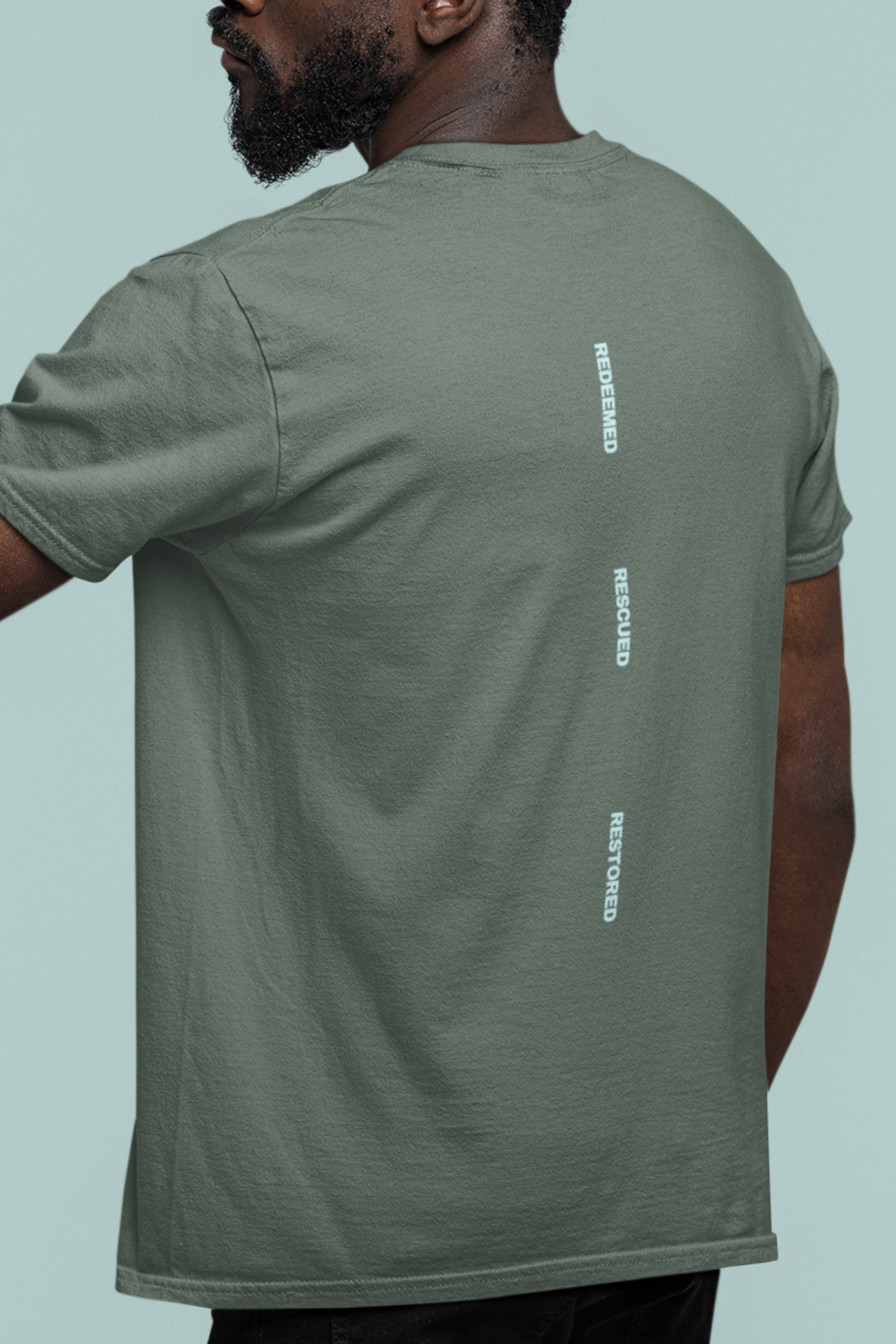 Person wearing a green t-shirt with bible verse on the back against a light blue background
